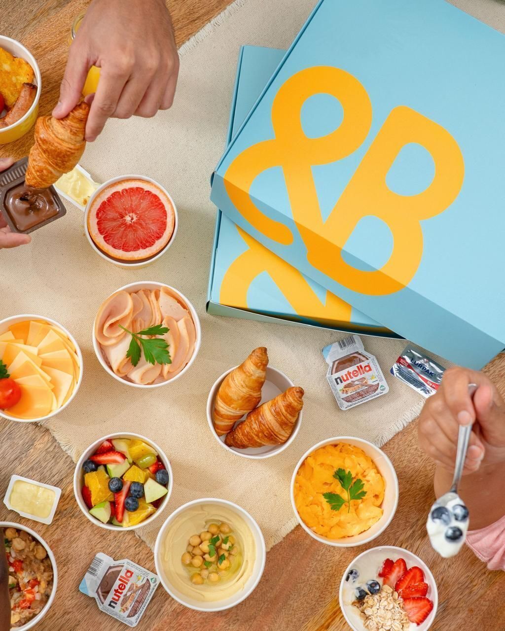 A variety of breakfast items including croissants, fruit, and Nutella spread on a table.