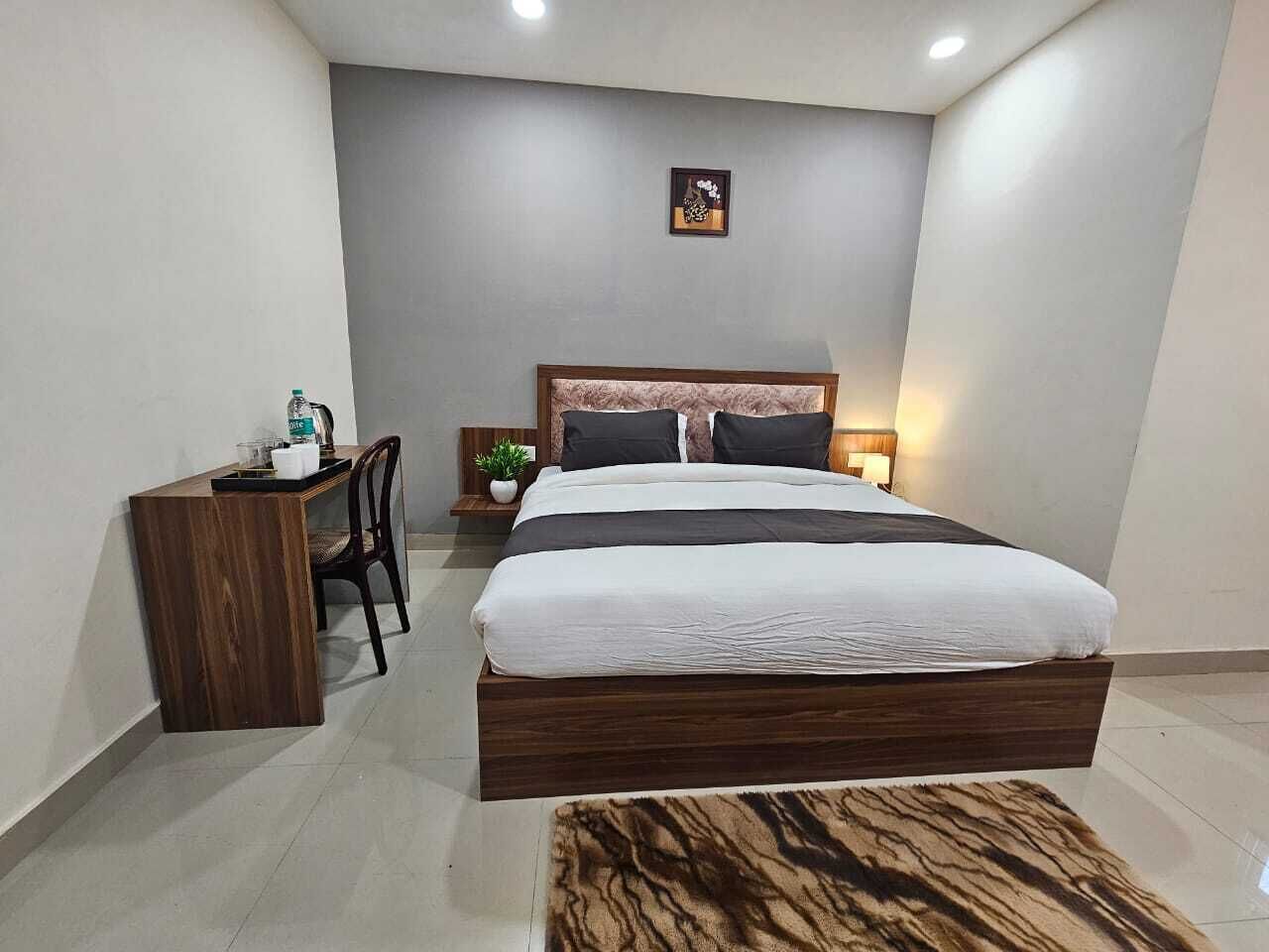 A modern bedroom with a large bed, a desk, and a small plant.