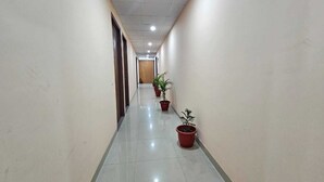 A long, narrow hallway with a tiled floor and potted plants along one side. - Hotel Vistacrest Noida Sector 104 (Noida)