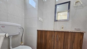 A bathroom with a toilet, a wooden cabinet, and a mirror. - Hotel Vistacrest Noida Sector 104 (Noida)