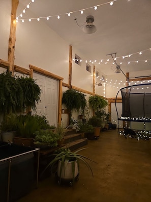 A room with wooden beams, white walls, and string lights. There are potted plants and a black chair. - Private Pool & Hot Tub | Fall color view for miles (Eureka Springs)