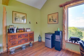 A room with a wooden cabinet, two refrigerators, a window with a view, and two framed pictures on the wall. - Private Pool & Hot Tub | Fall color view for miles (Eureka Springs)