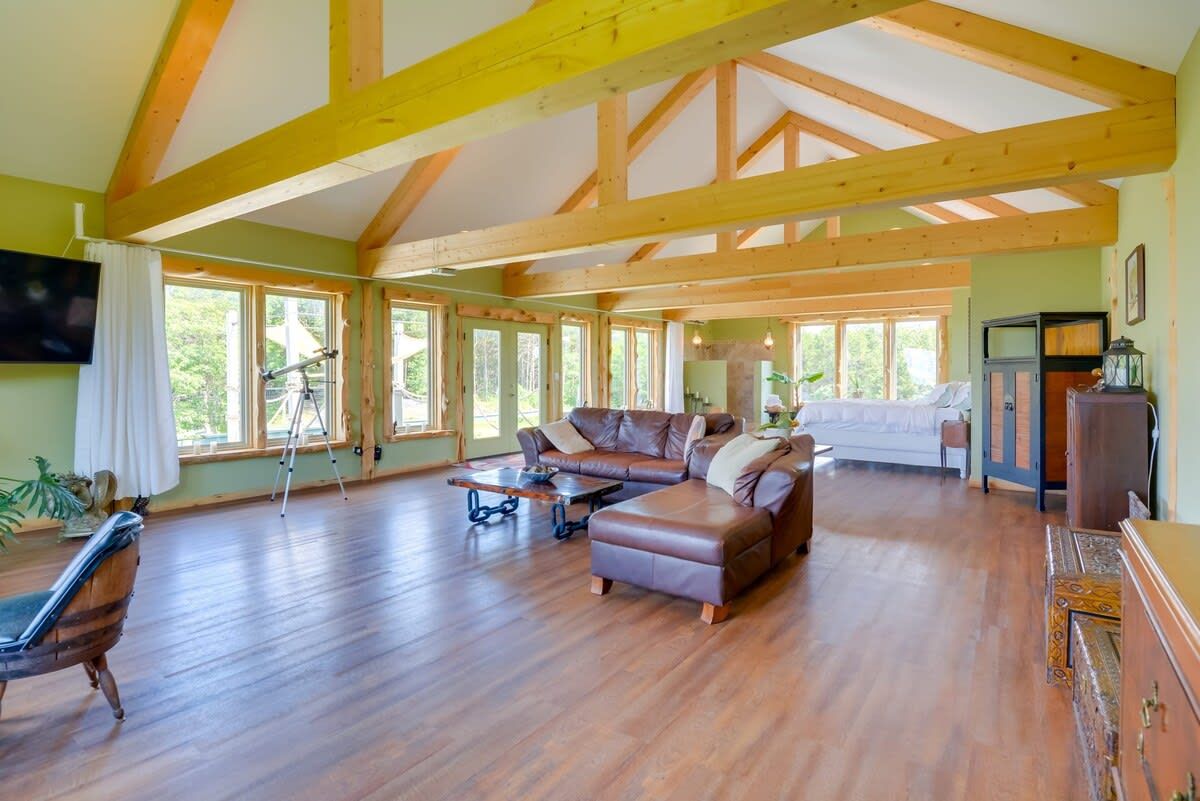 Un salon spacieux avec un plafond en bois, un grand canapé, une table à manger et un téléviseur fixé au mur.