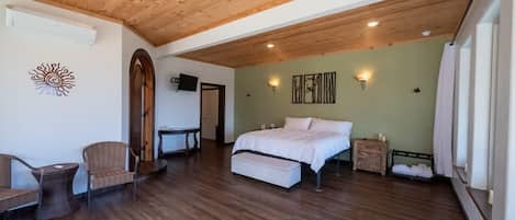 Une chambre spacieuse avec un plafond en bois, un lit, une petite table et une chaise.