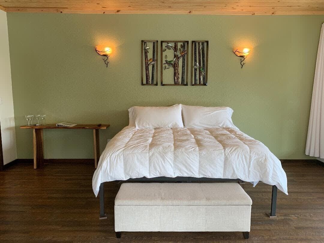 A bedroom with a bed, a bench, and wall-mounted lights.