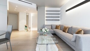 A modern living room with a grey sofa, a glass coffee table, and a vase of white flowers. - Italianway - Transiti 20 (Milan)