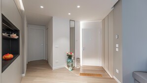 A modern hallway with wooden flooring, a vase with flowers, and a mirror on the wall. - Italianway - Transiti 20 (Milan)