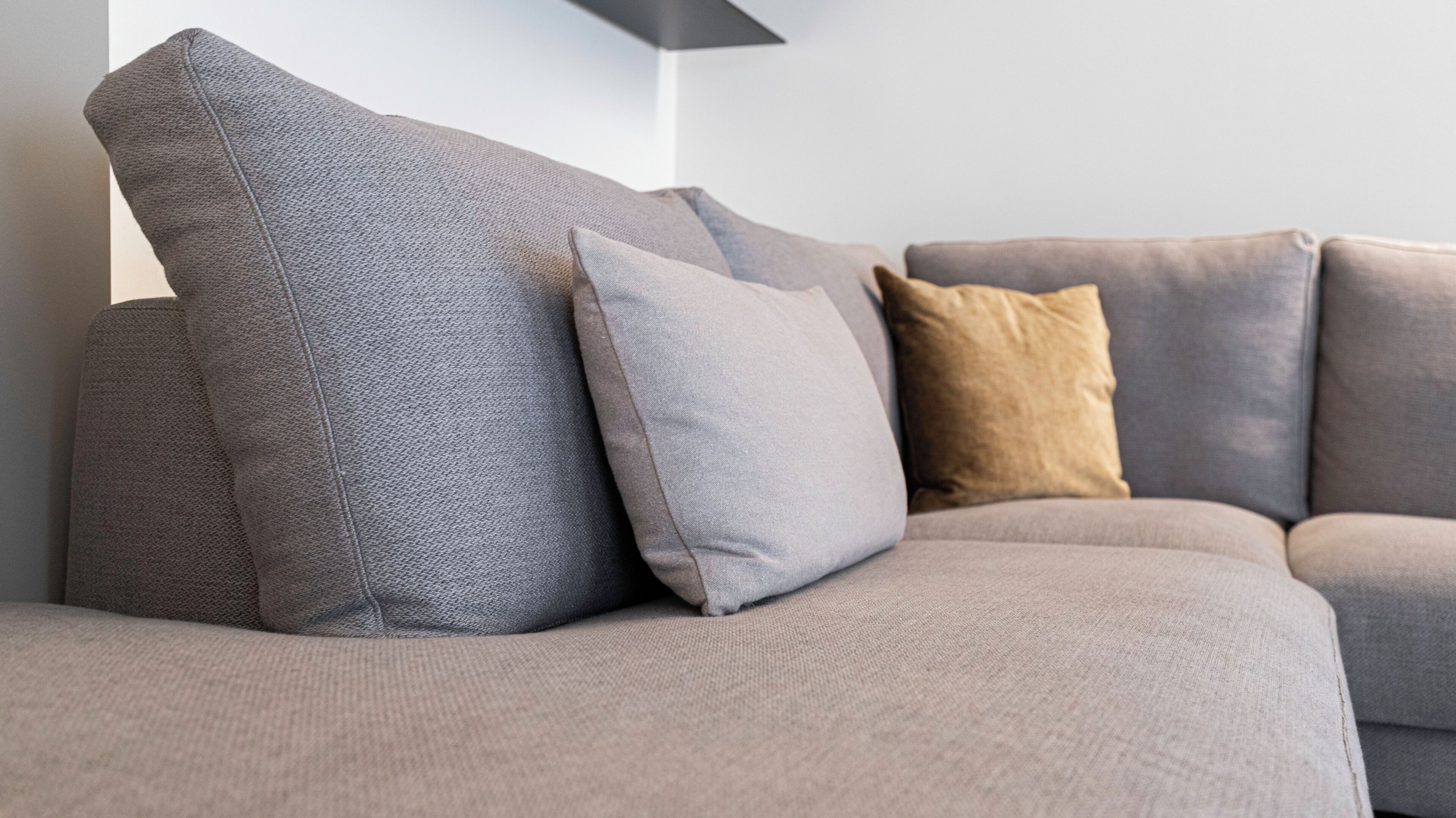 Un canapé gris avec trois coussins dans un salon moderne.