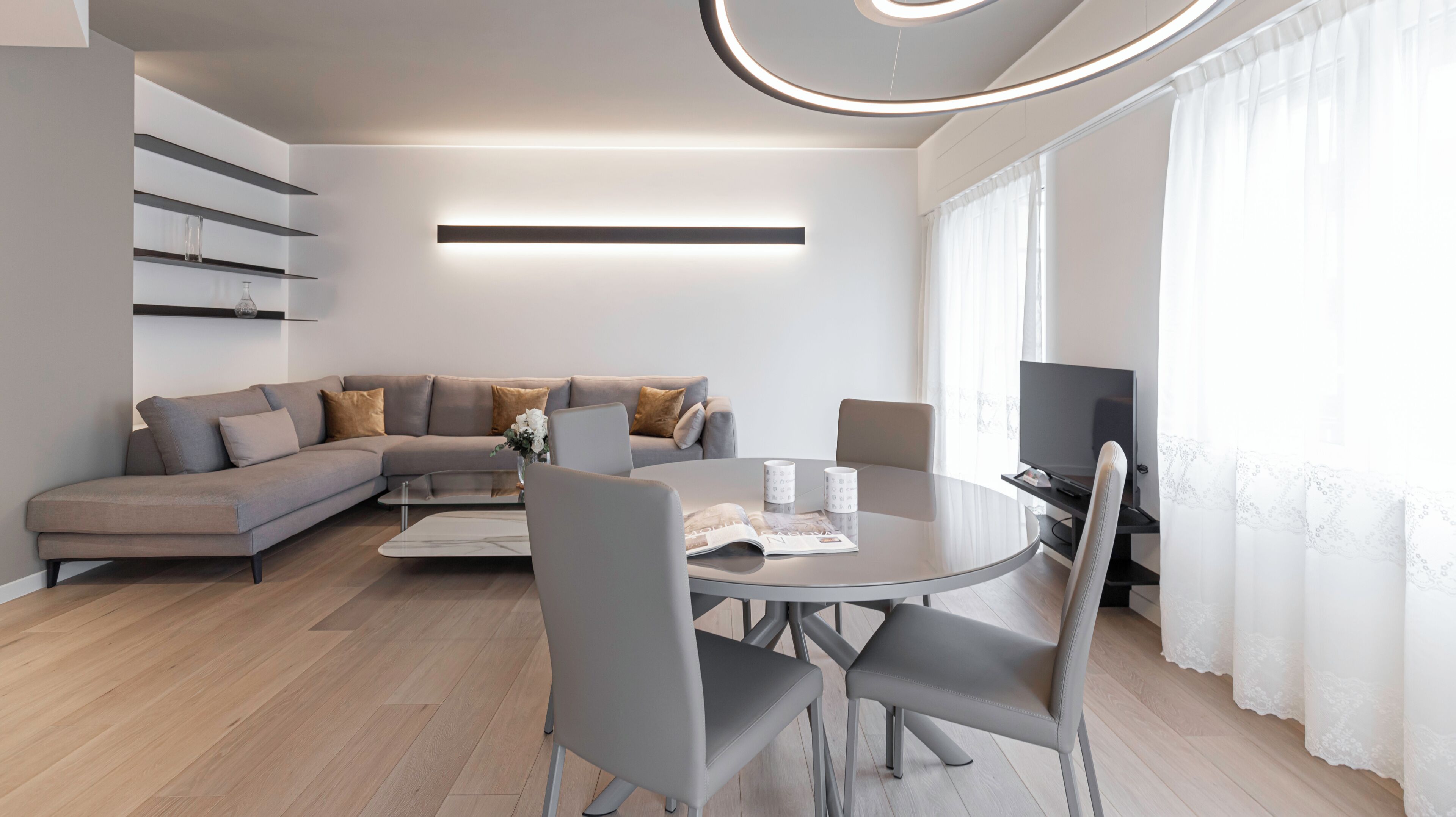 A modern living room with a grey sofa, a coffee table, and a TV.
