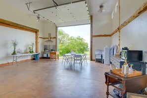 Une pièce spacieuse avec une grande table, des chaises, un téléviseur et une vue sur la verdure environnante.