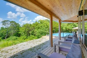 Une terrasse extérieure avec un plancher en bois, une piscine et une vue sur une zone boisée.