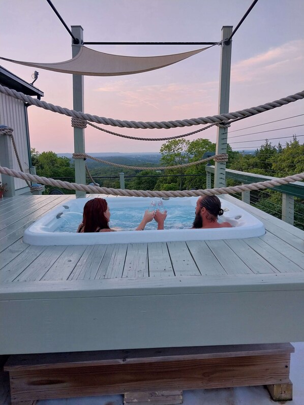 A hot tub on a wooden deck with a rope barrier and a view of the landscape.