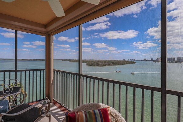 Relax on the balcony with a view of the bay, surrounded by wicker chairs and a cushioned bench.