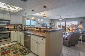 Una cocina moderna con una isla central, un comedor con vistas y una sala de estar con sofá y sillón reclinable.