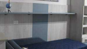 A modern bedroom with a bed, a wall-mounted shelf, and a decorative wall piece. - B&B Vista Normanna (Pietramontecorvino)