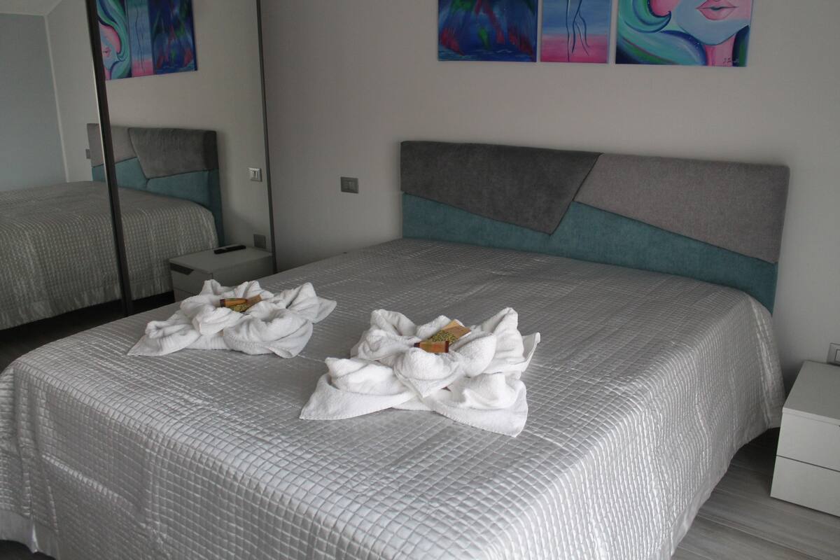 A hotel room with a large bed, a bedside table, and a nightstand.