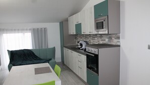 A modern kitchen with a microwave, oven, and sink. There is a dining area with a table and chairs. - B&B Vista Normanna (Pietramontecorvino)