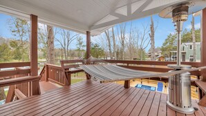 Une terrasse en bois avec un hamac, un radiateur d’extérieur et une vue sur un quartier résidentiel.
