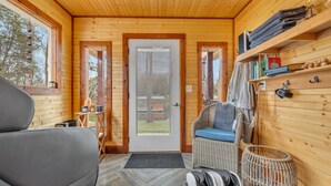 A cozy log cabin interior with a sofa, wicker chair, and a small table.