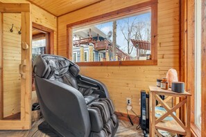 A massage chair in a wooden cabin with a view of a house through a window. - Lakefront, Heated Pool, Sauna, Sleeps 8! (Lebanon)