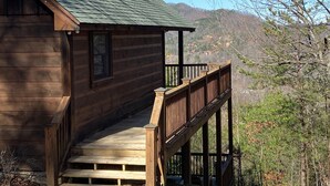 Een houten chalet met een balkon met uitzicht op een bergachtig landschap.