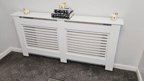 A white radiator with a decorative sign on top and two small golden ornaments. - Manchester 2-bed House, Sleeps 4, 20 Min to Centre (Manchester)