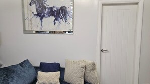 A living room with a dark blue sofa, a framed abstract painting, and a white door. - Manchester 2-bed House, Sleeps 4, 20 Min to Centre (Manchester)