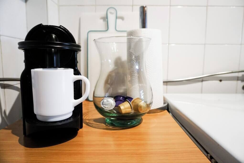 Una cafetera, una jarra de vidrio y un dispensador de toallas de papel sobre una encimera de cocina.