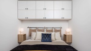 Ein Schlafzimmer mit einem Bett, Nachttischen, einem Kopfteil und einem Schrank darüber.