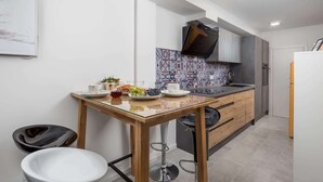 Eine moderne Küche mit einem Holztisch, Barhocker und einer gefliesten Spritzschutzwand.