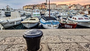 A marina filled with various boats docked in calm waters, with a historic town in the background.