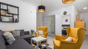 A modern living room with a sofa, armchairs, a coffee table, and a bookshelf.
