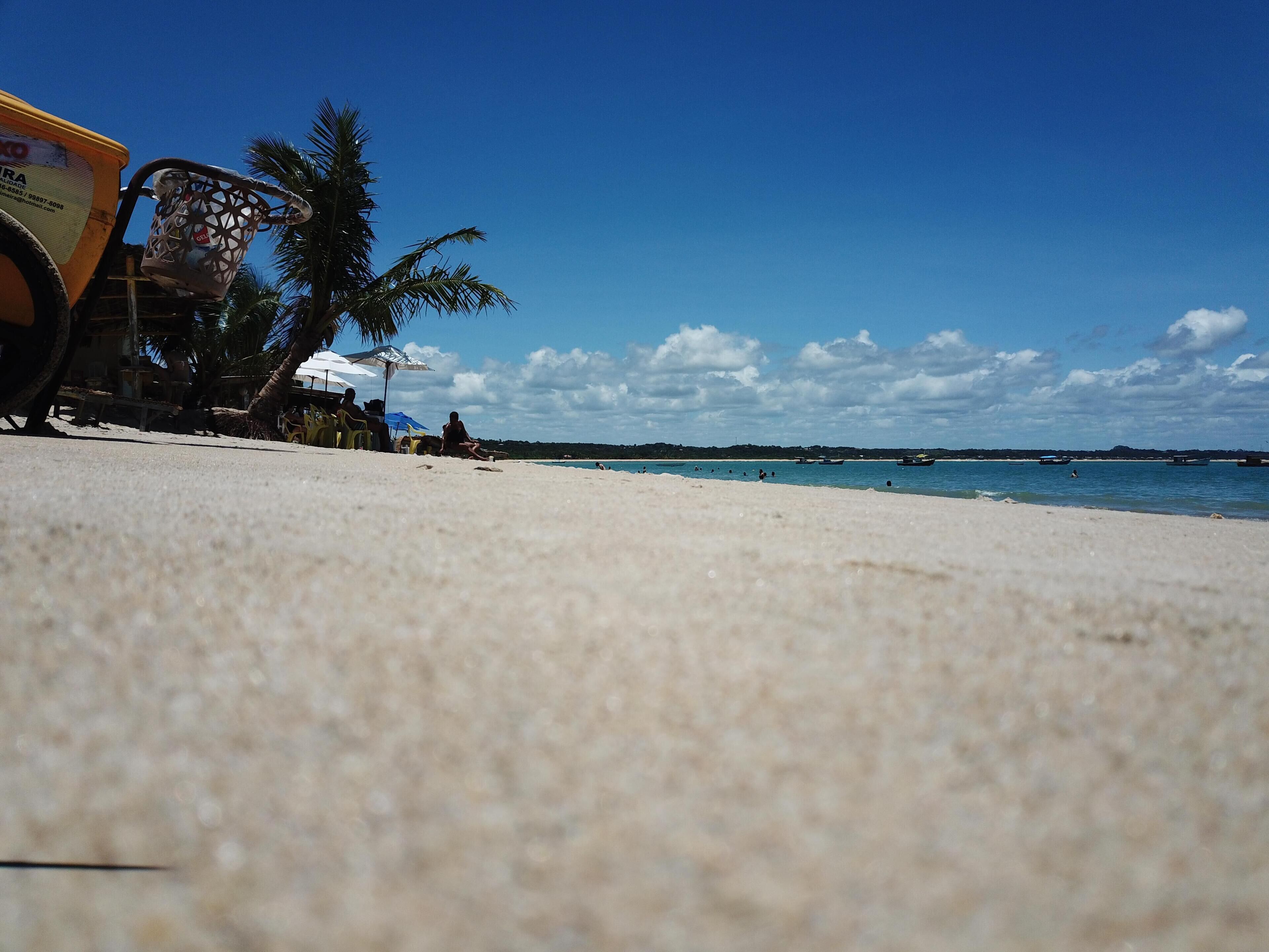 Una spiaggia sabbiosa con alcune persone e un veicolo parcheggiato.