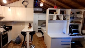 A compact kitchen with white cabinets, a dining table, and a small island with stools. - Lovely 1-bed Chalet in Mutari/santa Cruz Cabralia (Santa Cruz Cabralia)