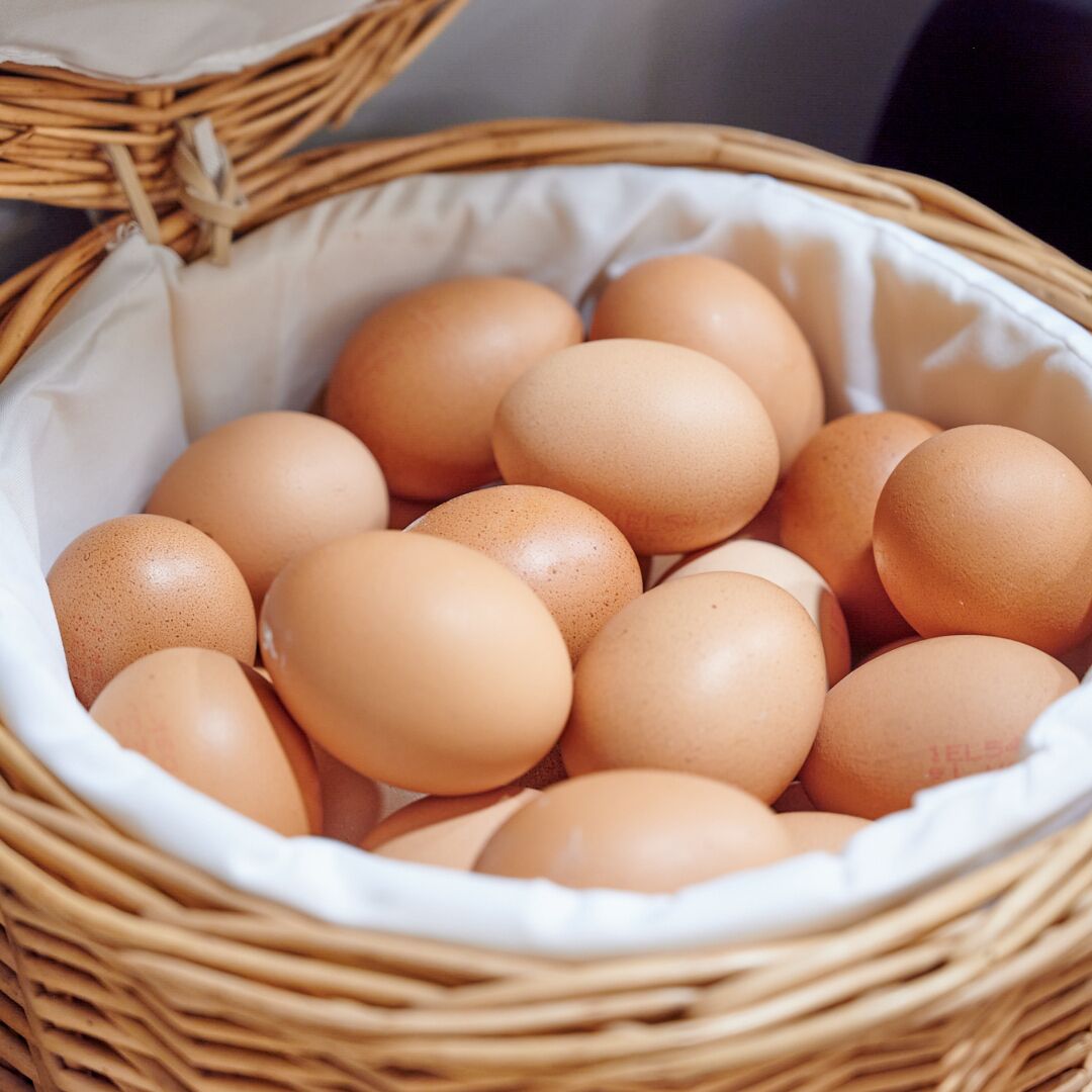 Una cesta de mimbre llena de huevos.