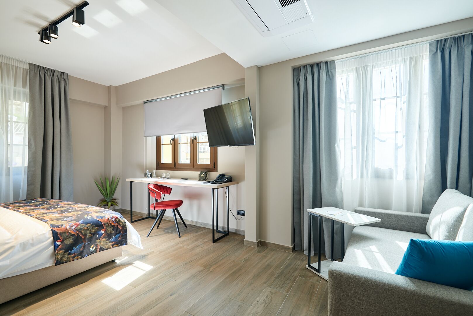 Une chambre d’hôtel équipée d’un lit, d’un bureau, d’une chaise, d’une télévision et d’un petit coin salon.