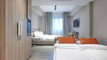 A hotel room with a bed, a desk, a chair, a TV, and a window with curtains.
