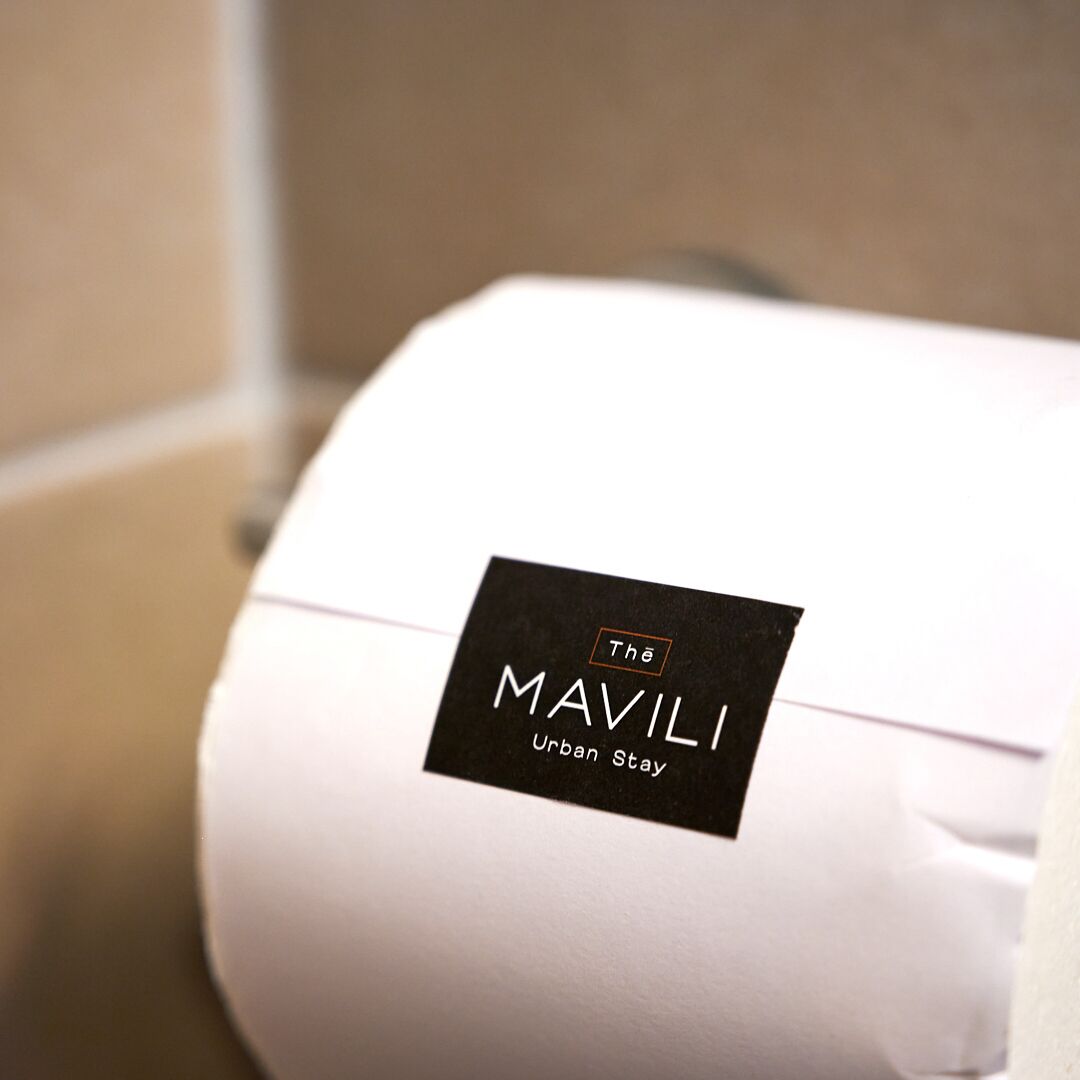 A white suitcase with a black label that reads "The MAVILI Urban Stay."