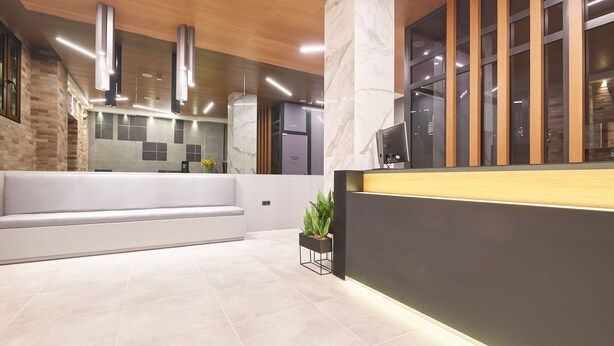 Un espace d’accueil moderne avec un comptoir de réception en marbre, un coin salon avec un canapé blanc et une plante en pot.