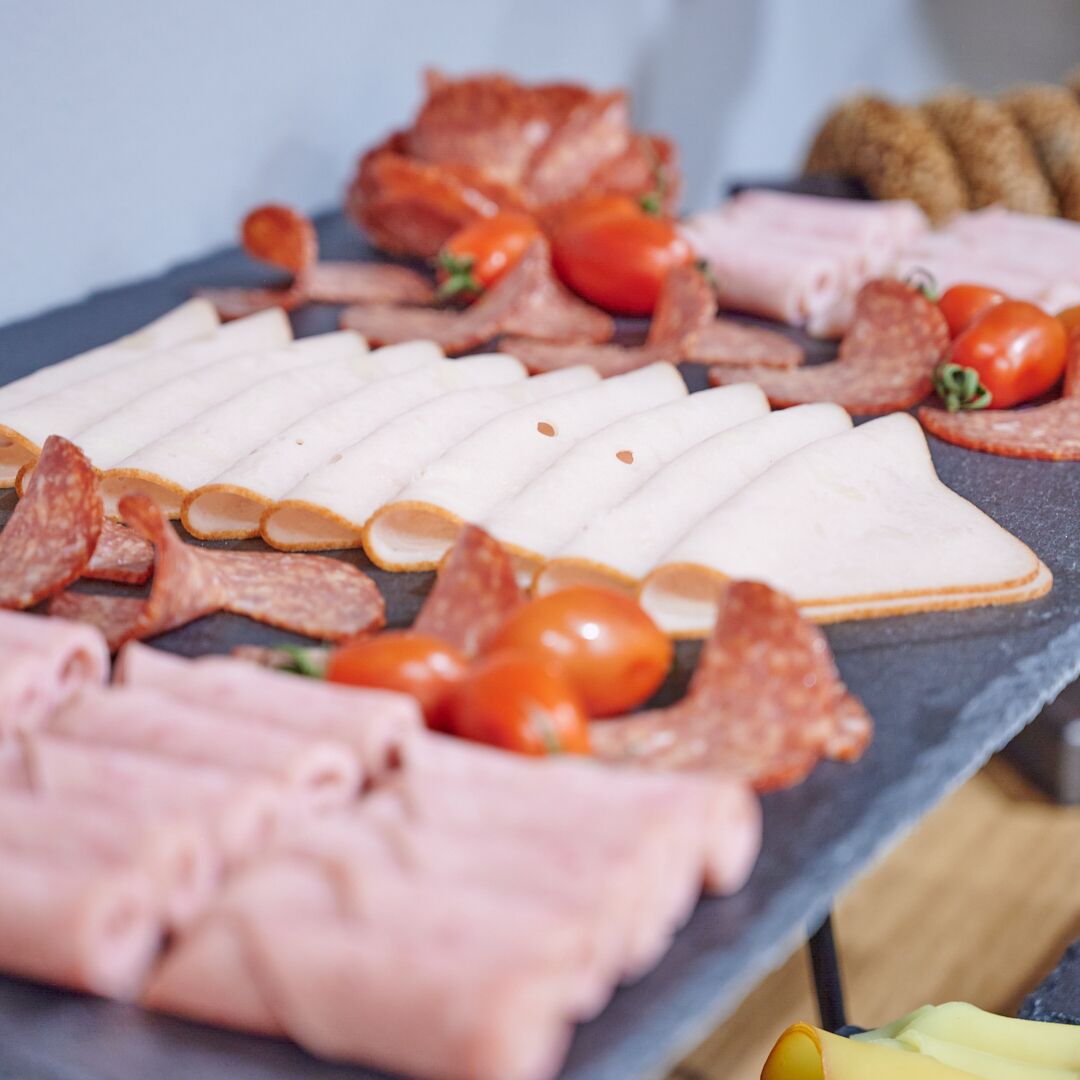 A variety of meats and cheeses arranged on a slate board.