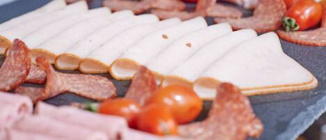 A variety of meats and cheeses arranged on a slate board.