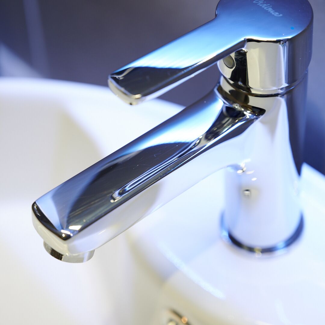 A chrome faucet with a single lever handle, attached to a white sink.