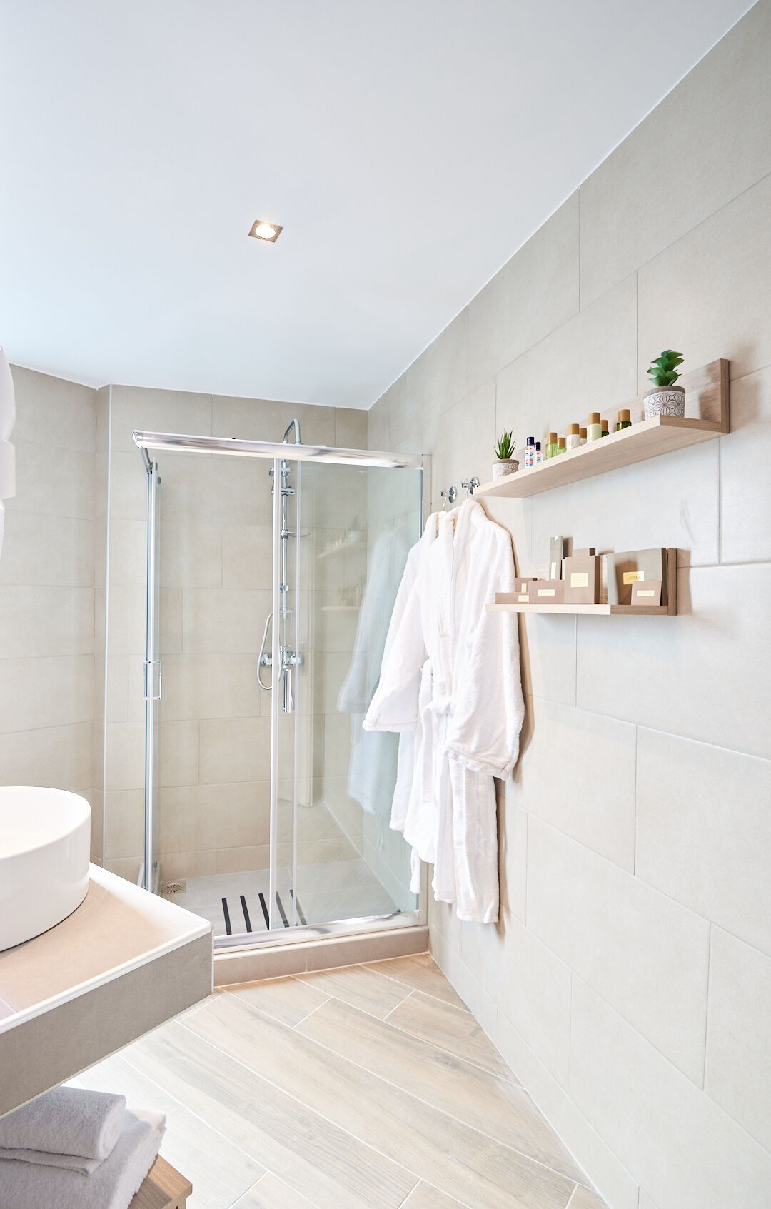 Une salle de bain moderne avec une douche à parois de verre, un lavabo blanc et un meuble-lavabo en bois.