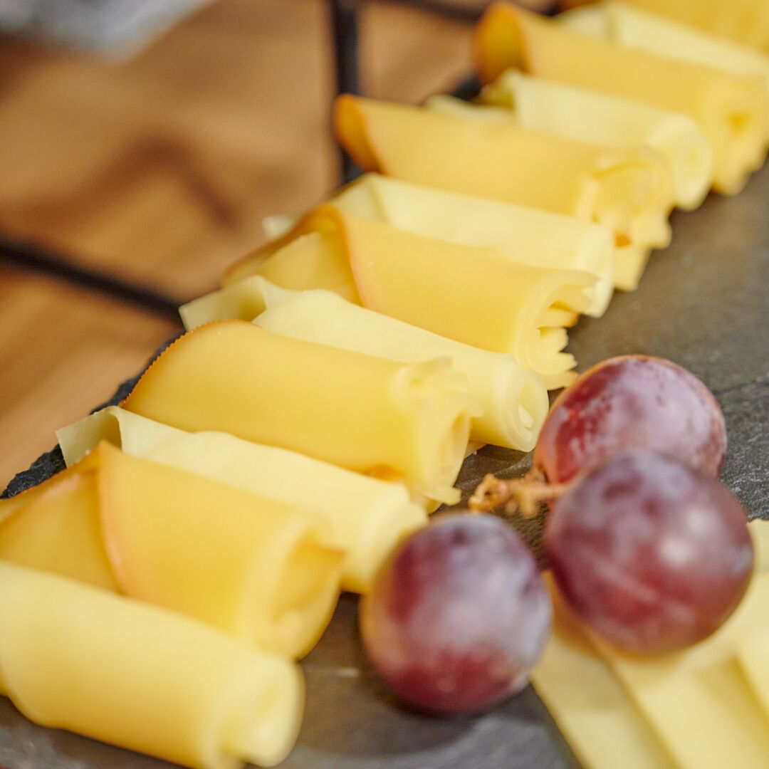 A tray of yellow pasta rolls and grapes on a slate surface.