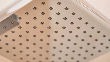 Primer plano de un panel de techo metálico perforado, probablemente parte de un sistema de ducha o ventilación.