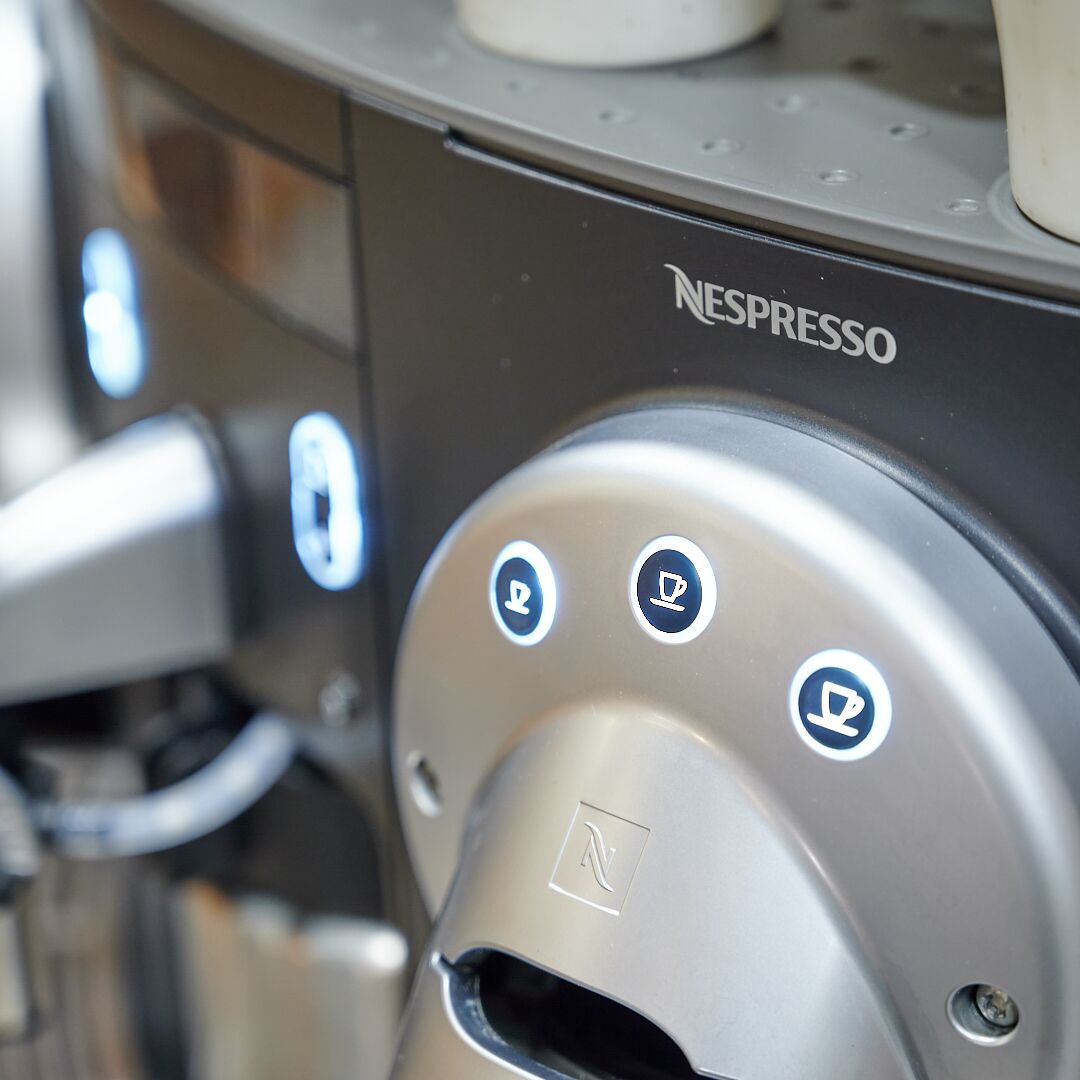 Primer plano de una máquina de café Nespresso con un panel de control que tiene tres botones.
