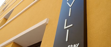 A building with a sign that reads "Urban Stay" on a yellow wall.