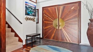 Eine Treppe mit hölzernen Geländern, einem runden Teppich und einer großen Holztür mit Sonnendesign.