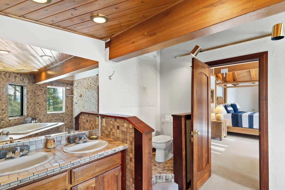 A bathroom with a large mirror, two sinks, and a wooden vanity.