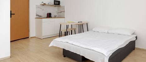 Un dormitorio con una cama, un escritorio con una silla, un microondas y una cafetera.